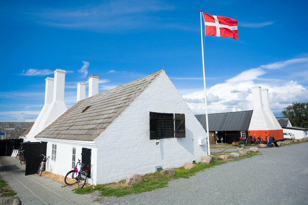 biały domek po powiewającą czerwoną duńską flagą